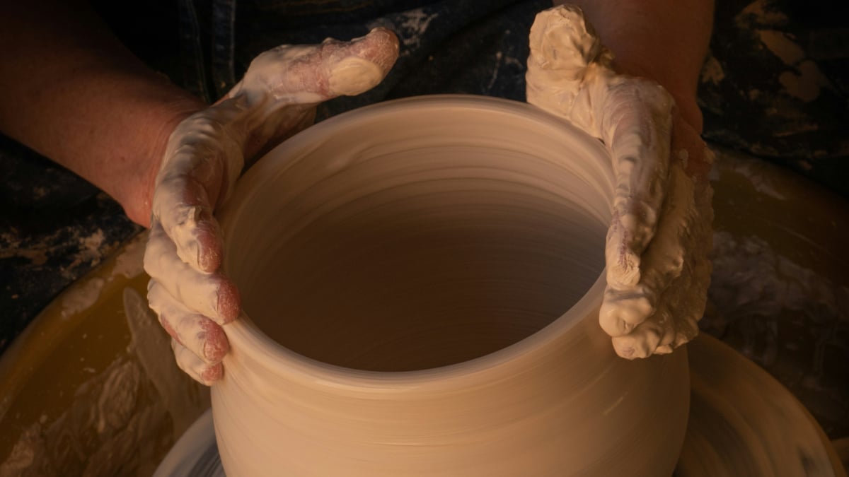 A photograph of a person making clay pottery.